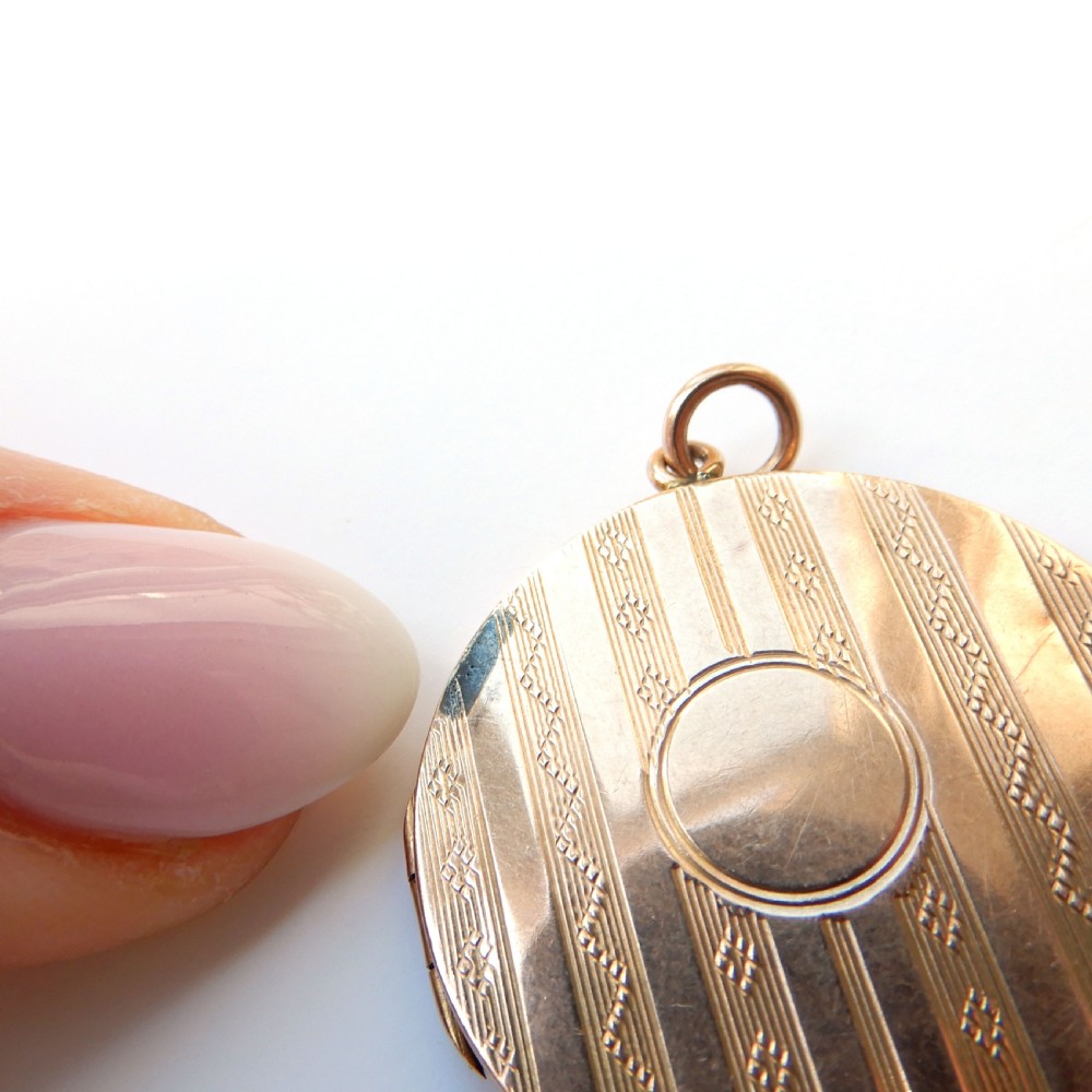 A round 9ct gold back and front locket featuring engine-turned diagonal line engraving and an unengraved central circular cartouche. View V