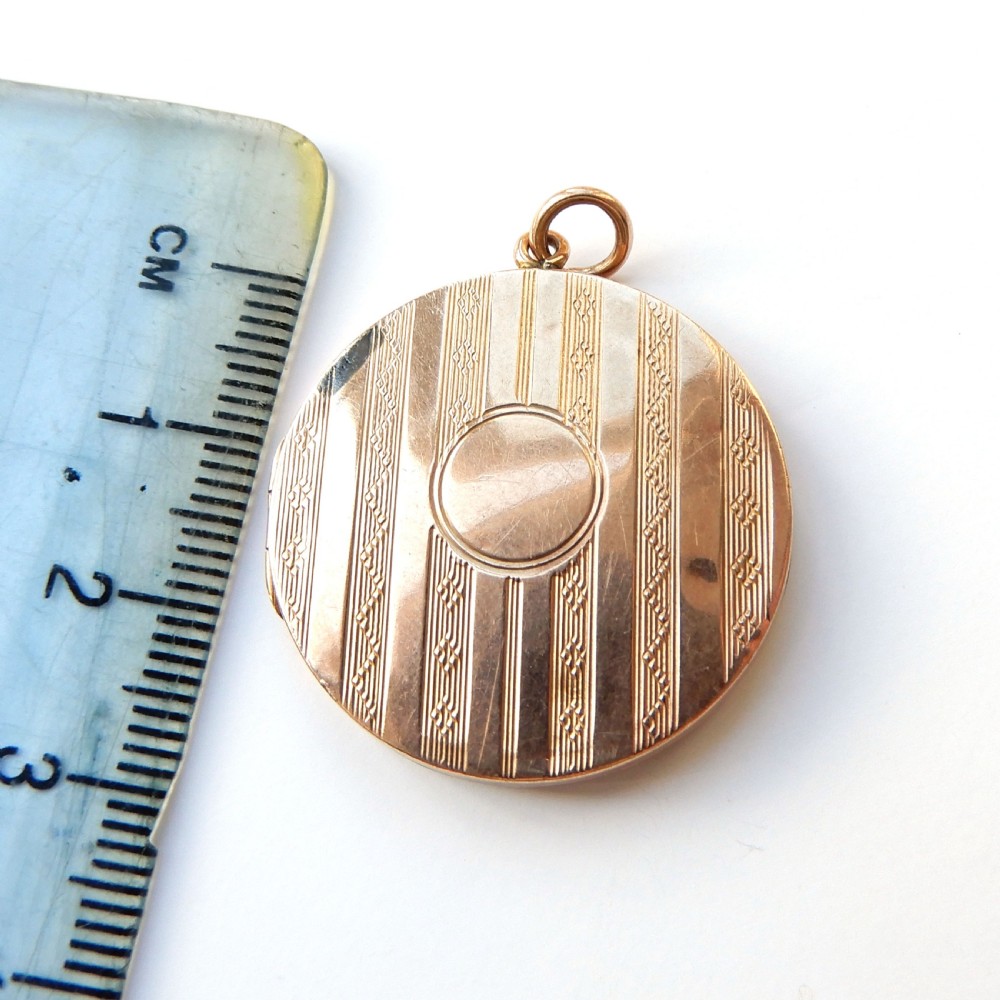 A round 9ct gold back and front locket featuring engine-turned diagonal line engraving and an unengraved central circular cartouche. View VI