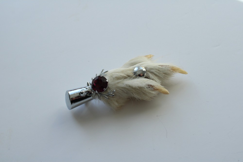 A Scottish grouse foot brooch mounted in a silver-tone metal cap featuring a faceted purple rhinestone. View IV