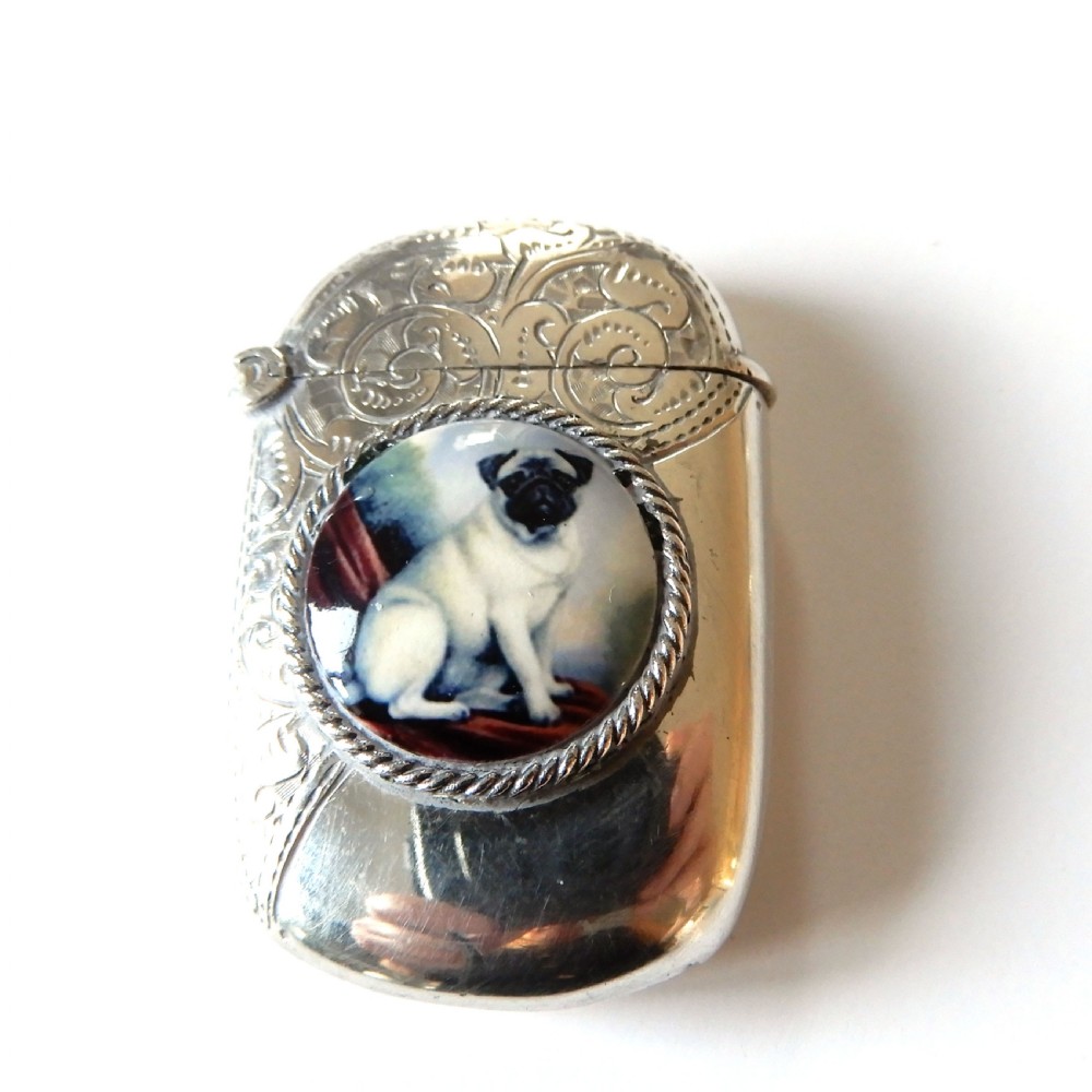 A sterling silver vesta case featuring an engraved top section, a rope-twist border, and a central enamel plaque depicting a sitting pug dog. View IV