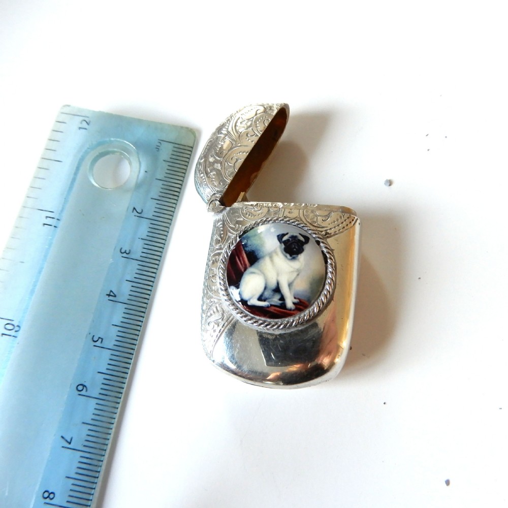 A sterling silver vesta case featuring an engraved top section, a rope-twist border, and a central enamel plaque depicting a sitting pug dog. View VI