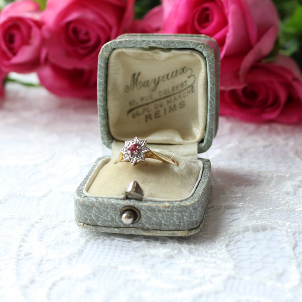 An antique 18ct yellow gold ring featuring a central red ruby surrounded by diamonds set in a six-pointed star shape.