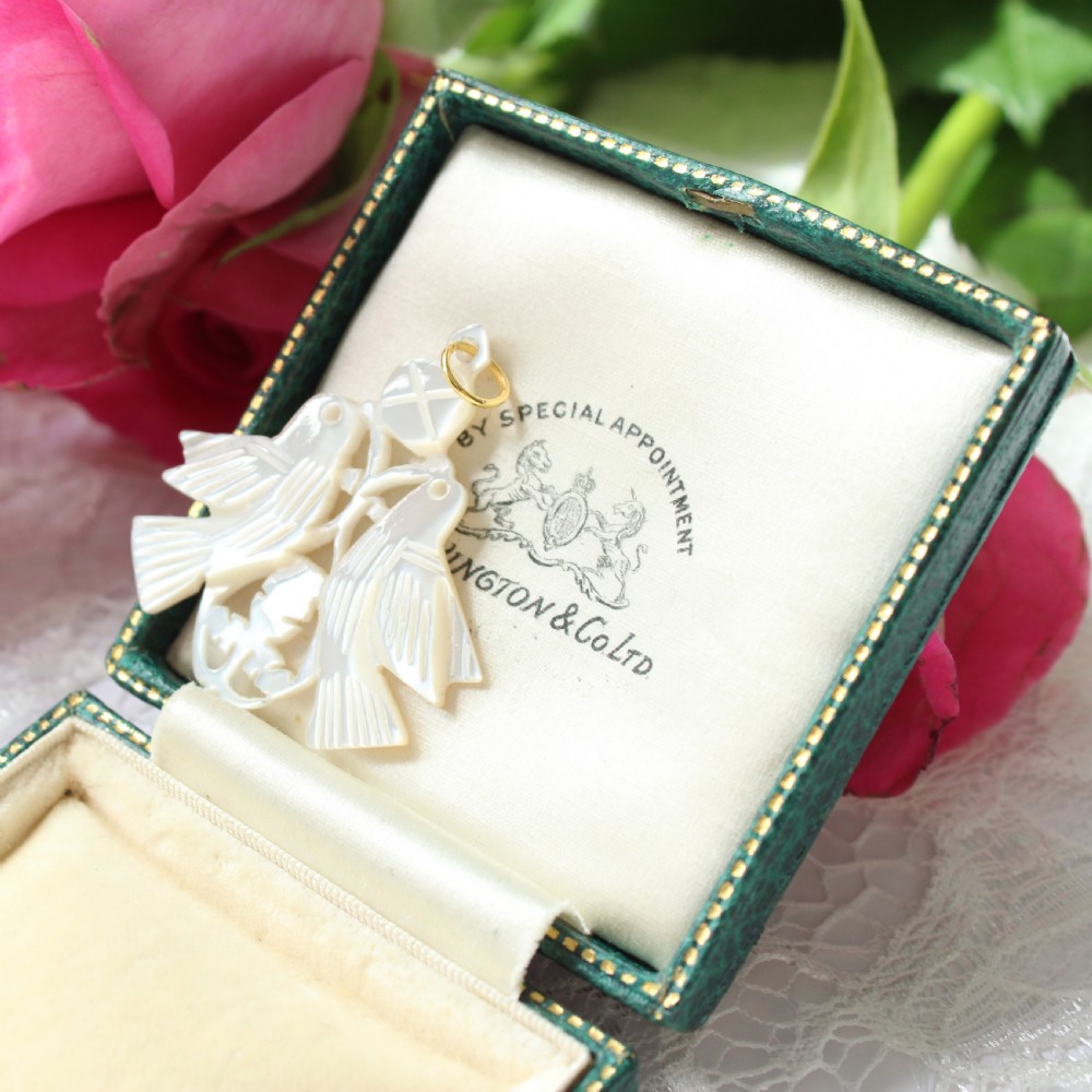 An intricately hand-carved mother-of-pearl pendant depicting two doves with detailed feather work and a gold suspension bail.
