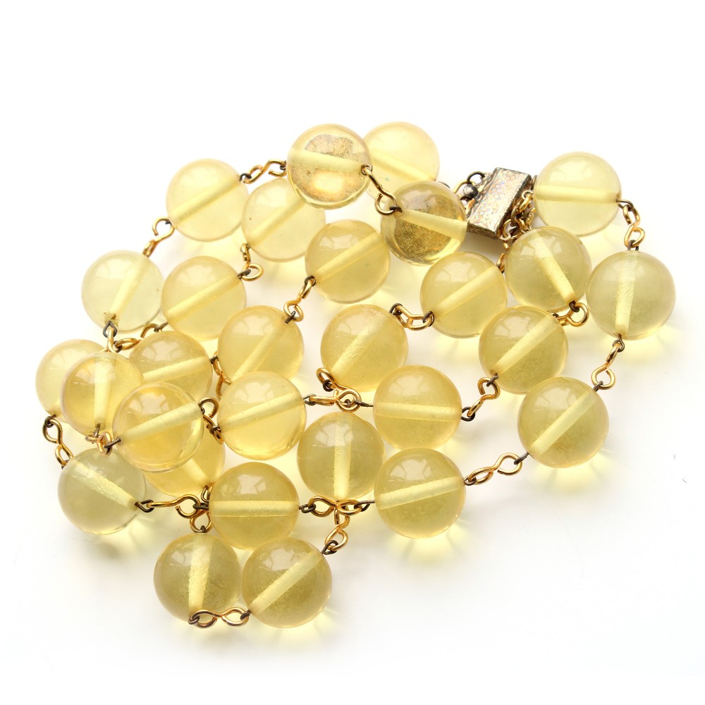 A mid-century necklace featuring spherical translucent yellow Lucite beads connected by brass wire links with a box clasp.