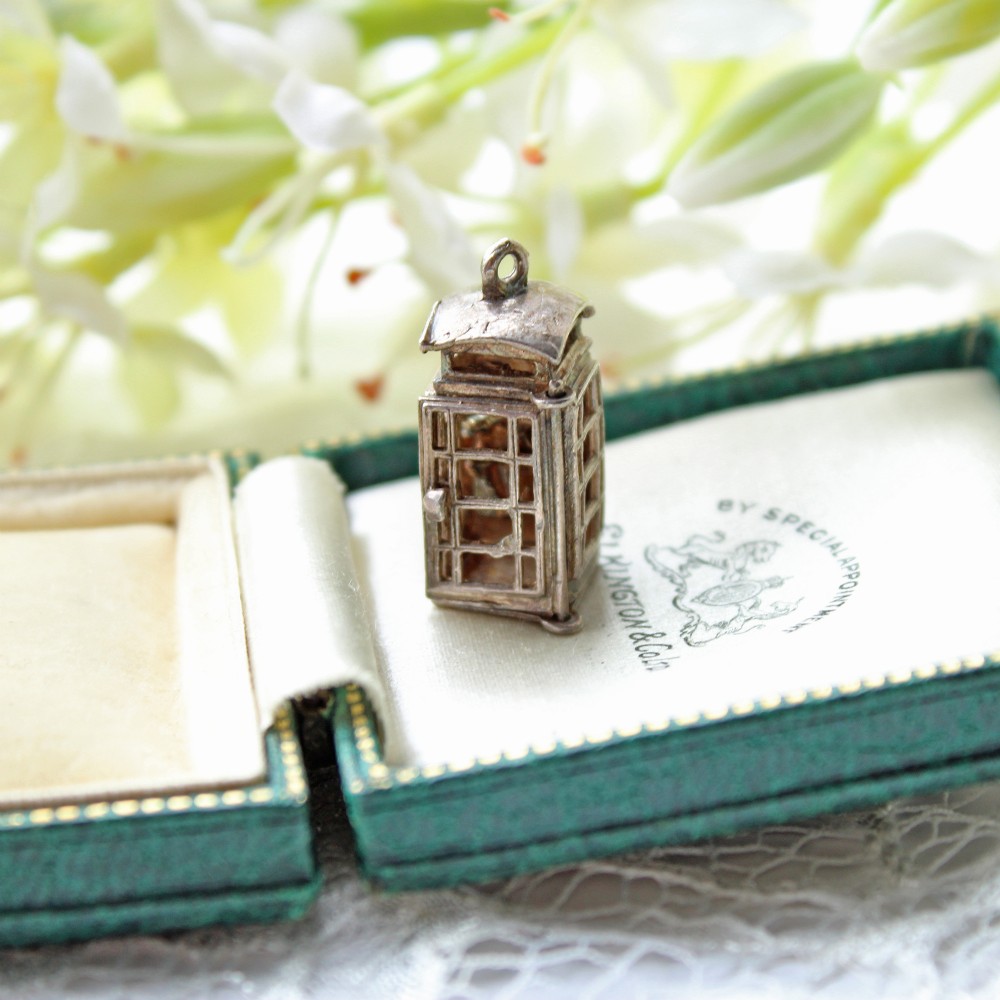 A miniature sterling silver charm detailed in the form of a traditional British telephone kiosk with an attachment loop at the top.