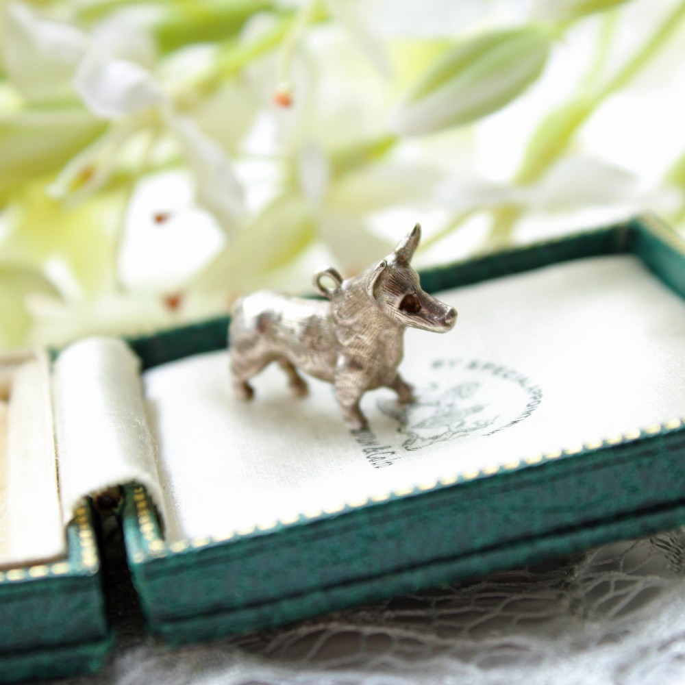A small sterling silver charm shaped like a standing Corgi dog with textured fur and a top attachment loop.