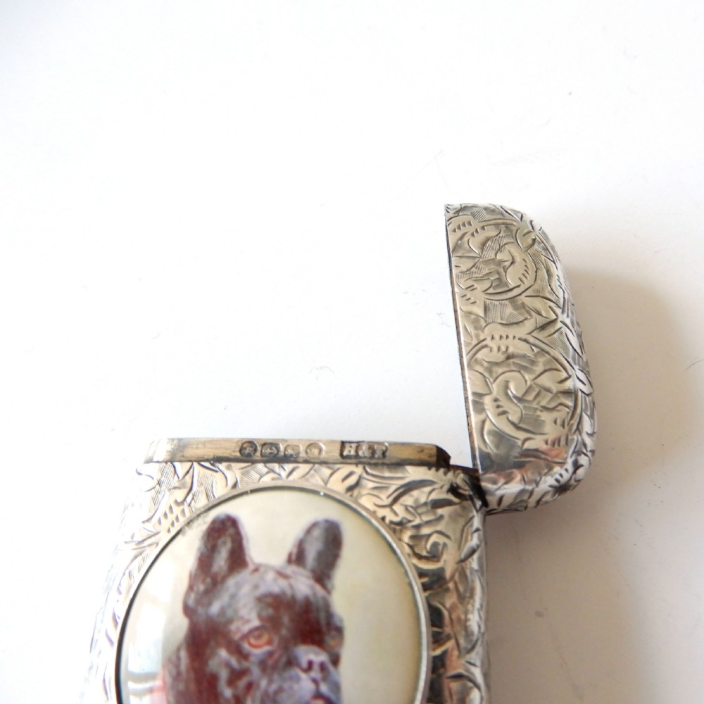 An antique Victorian sterling silver vesta case decorated with foliage engraving and a central circular enamel plaque depicting a French Bulldog. View V