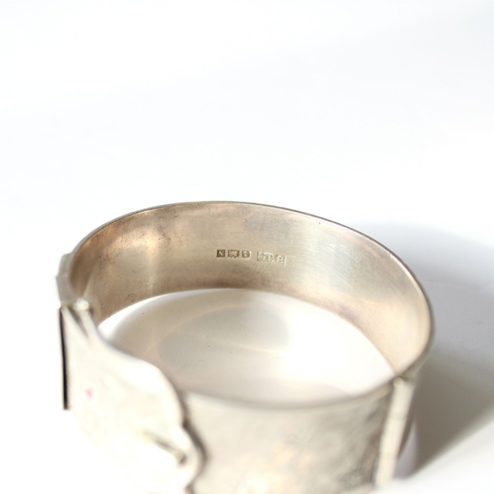 A wide sterling silver hinged buckle bangle featuring engraved starburst patterns set with round red rubies. View IV