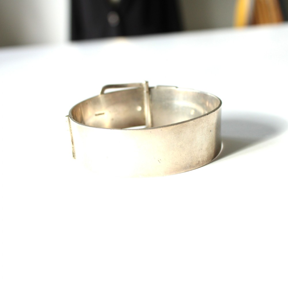 A wide sterling silver hinged buckle bangle featuring engraved starburst patterns set with round red rubies. View V