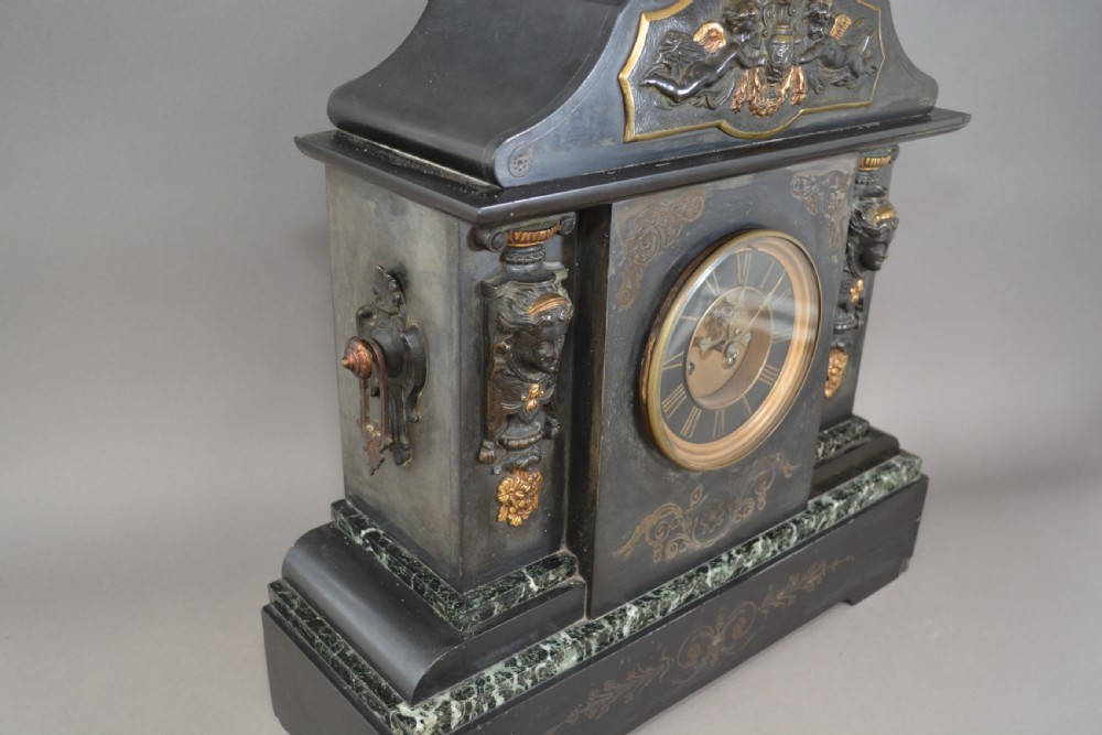 A Victorian black slate and green marble mantel clock featuring bronze mounts, gilt etched scrollwork, and classical cherub reliefs. View II