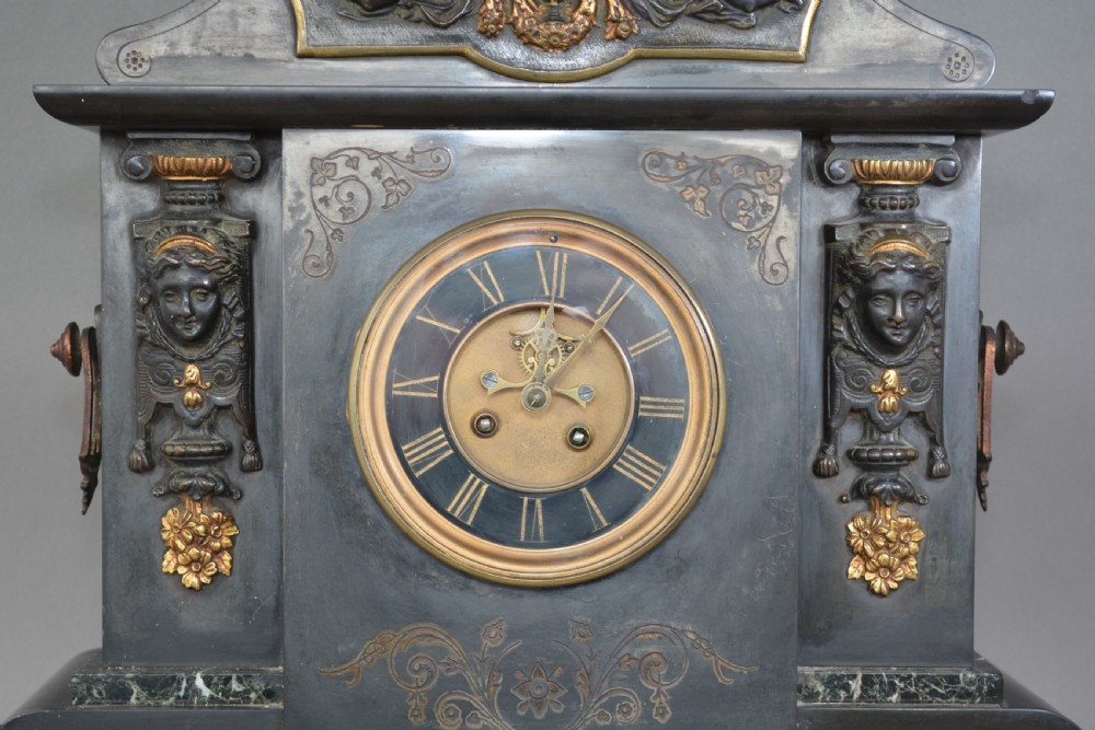 A Victorian black slate and green marble mantel clock featuring bronze mounts, gilt etched scrollwork, and classical cherub reliefs. View III