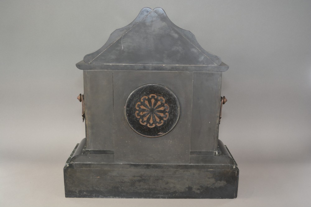 A Victorian black slate and green marble mantel clock featuring bronze mounts, gilt etched scrollwork, and classical cherub reliefs. View V