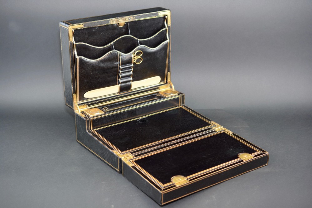 A rectangular black leather Victorian writing box featuring gilt-tooled border lines, a top brass carrying handle, and a central brass keyhole escutcheon. View III