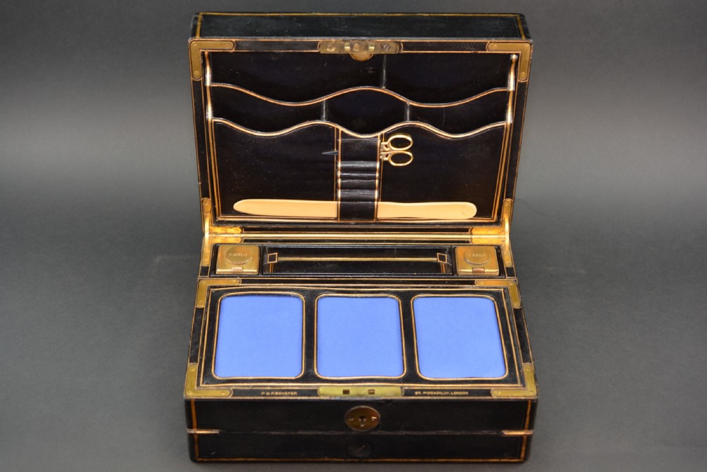 A rectangular black leather Victorian writing box featuring gilt-tooled border lines, a top brass carrying handle, and a central brass keyhole escutcheon. View IV