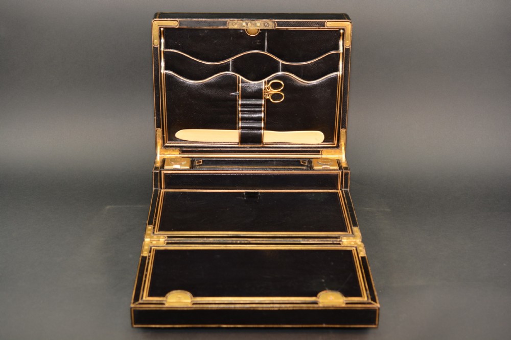 A rectangular black leather Victorian writing box featuring gilt-tooled border lines, a top brass carrying handle, and a central brass keyhole escutcheon. View V