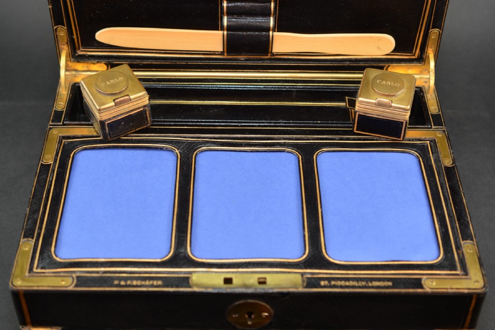 A rectangular black leather Victorian writing box featuring gilt-tooled border lines, a top brass carrying handle, and a central brass keyhole escutcheon. View VI