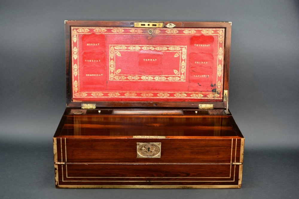 Top view of a rectangular dark rosewood writing slope decorated with brass border stringing and a central brass cartouche. View II