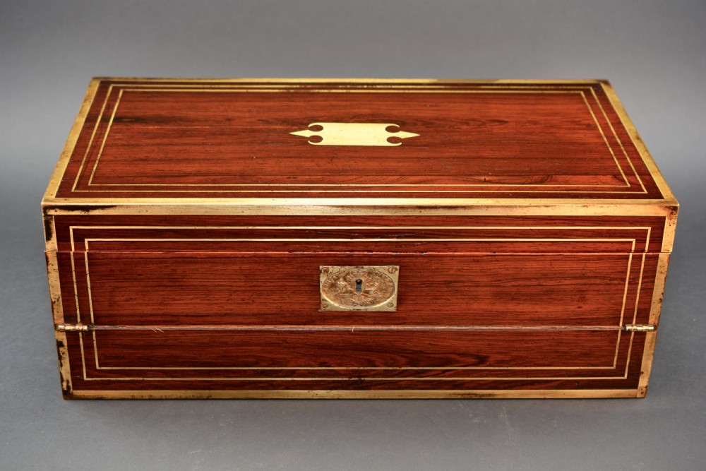 Top view of a rectangular dark rosewood writing slope decorated with brass border stringing and a central brass cartouche. View IV