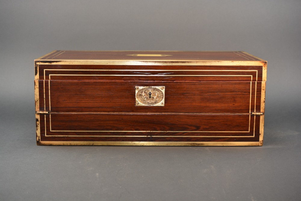 Top view of a rectangular dark rosewood writing slope decorated with brass border stringing and a central brass cartouche. View V