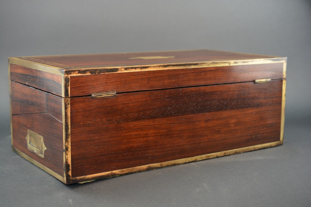 Top view of a rectangular dark rosewood writing slope decorated with brass border stringing and a central brass cartouche. View VI