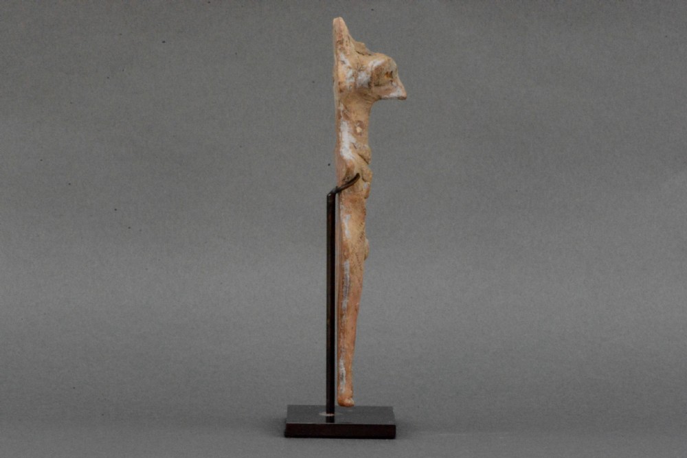 An ancient Syro-Hittite terracotta figure of the goddess Astarte featuring a bird-like face and incised geometric body markings mounted on a black stand. View II