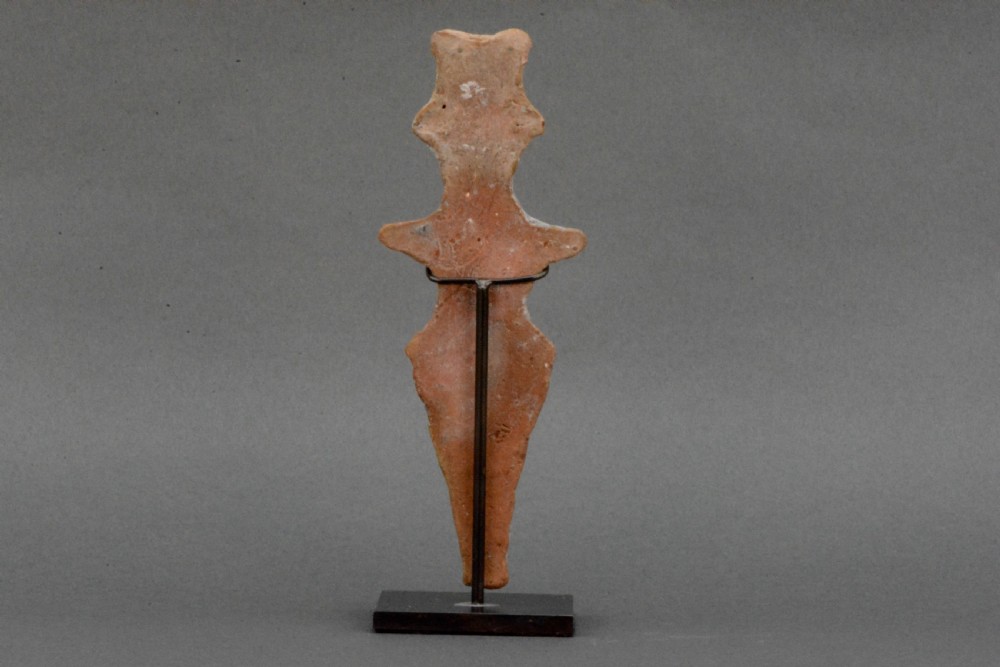 An ancient Syro-Hittite terracotta figure of the goddess Astarte featuring a bird-like face and incised geometric body markings mounted on a black stand. View III