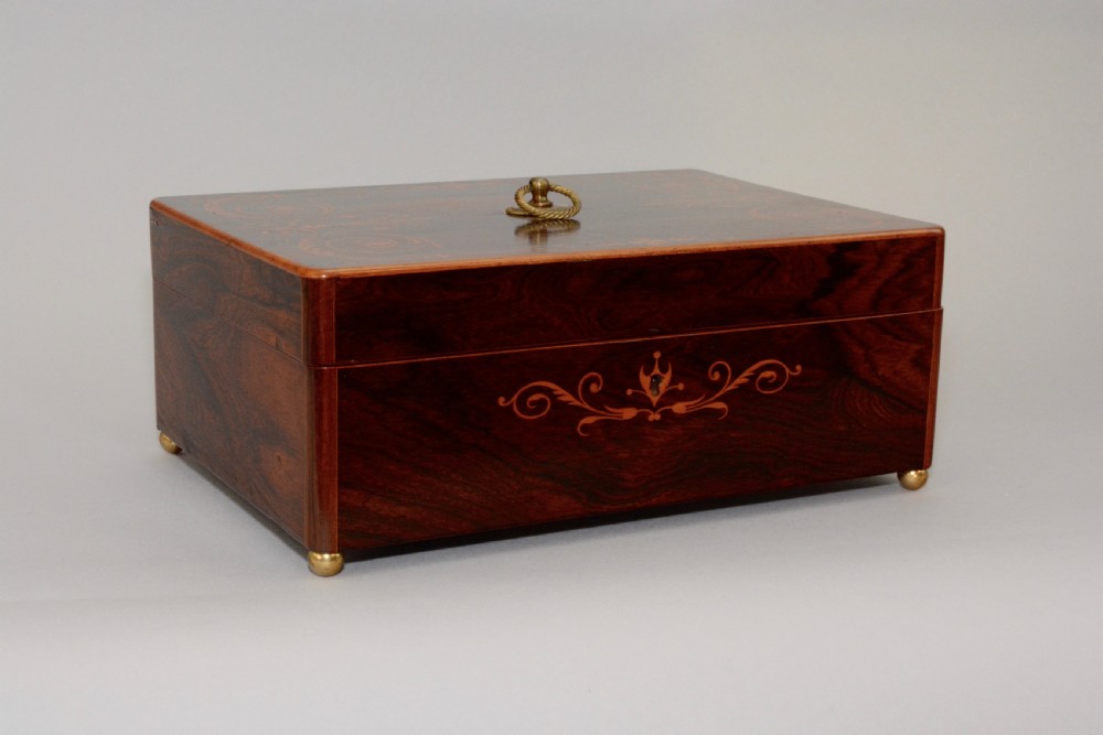 A rectangular dark reddish-brown rosewood box featuring fine wood marquetry around the keyhole, a top brass ring handle, and brass ball feet. View II