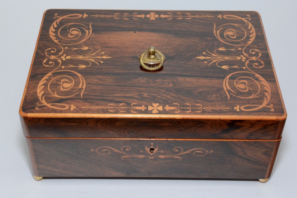 A rectangular dark reddish-brown rosewood box featuring fine wood marquetry around the keyhole, a top brass ring handle, and brass ball feet. View IV