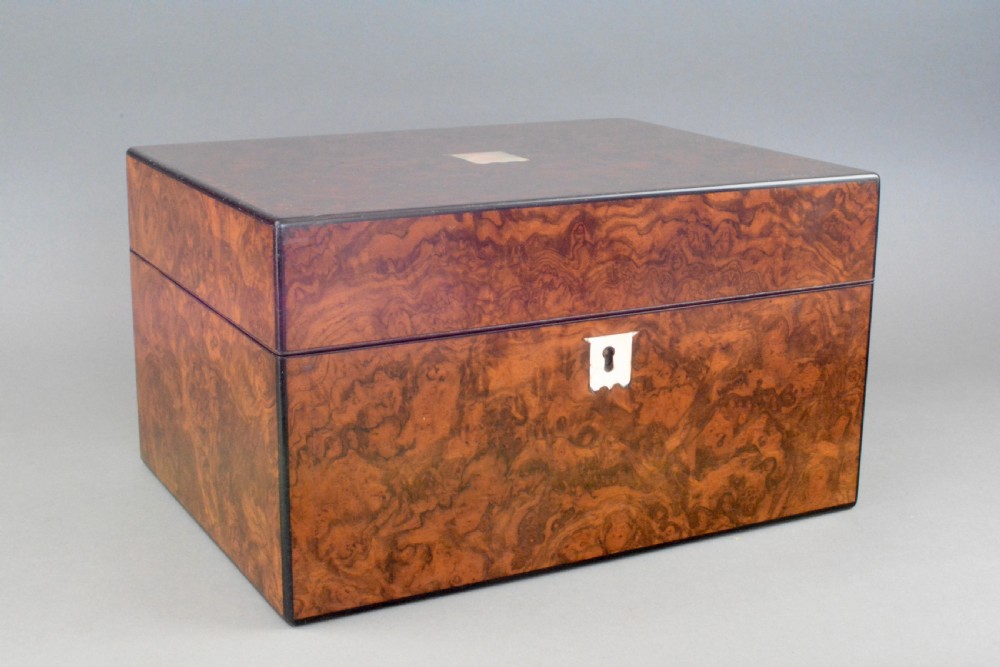 A rectangular Victorian figured walnut dressing box featuring a mother-of-pearl escutcheon and lid inlay against a plain grey background.