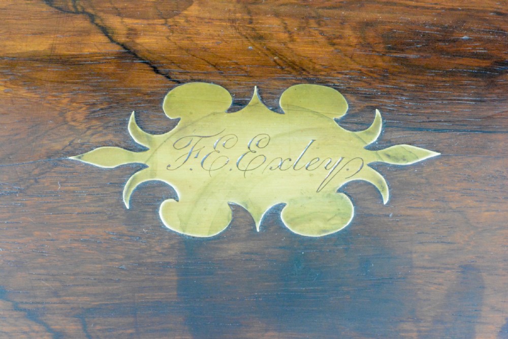 A rectangular dark wood writing slope box with flush brass corner brackets, a brass keyhole escutcheon, and an inlaid top plaque. View II