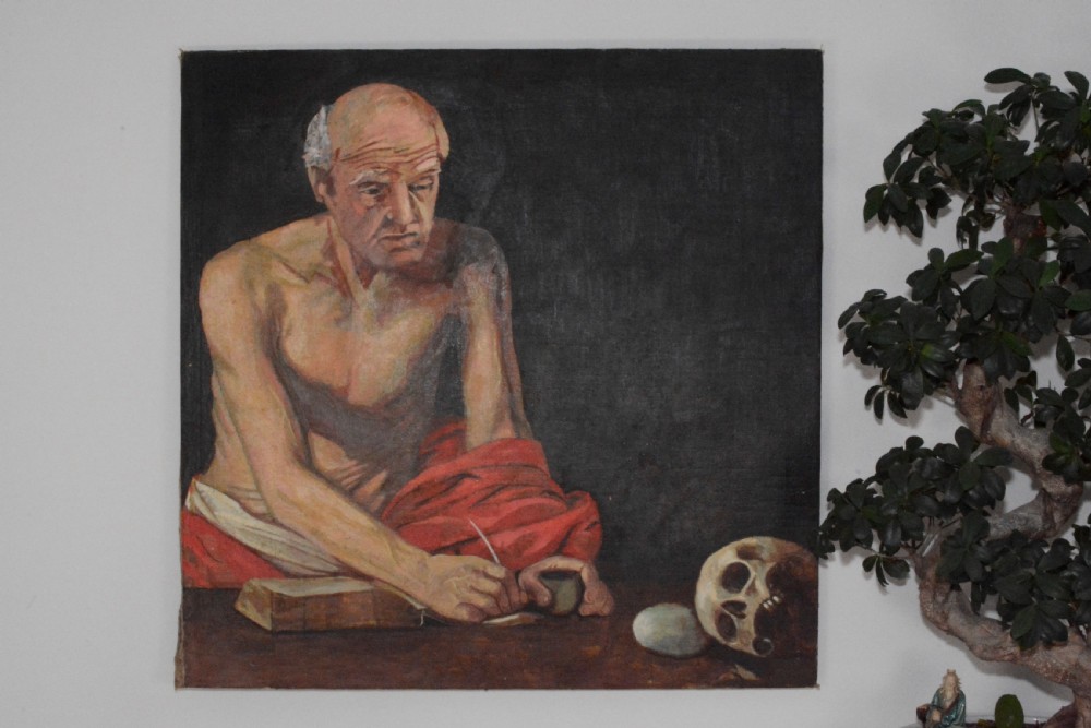 An oil painting on canvas depicting Saint Jerome writing in a book beside a human skull and stone against a dark background. View III