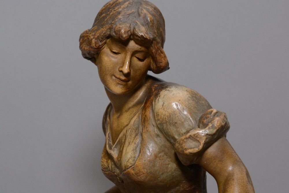 An Art Nouveau terracotta sculpture depicting a seated country maiden in draped clothing beside a woven basket. View V