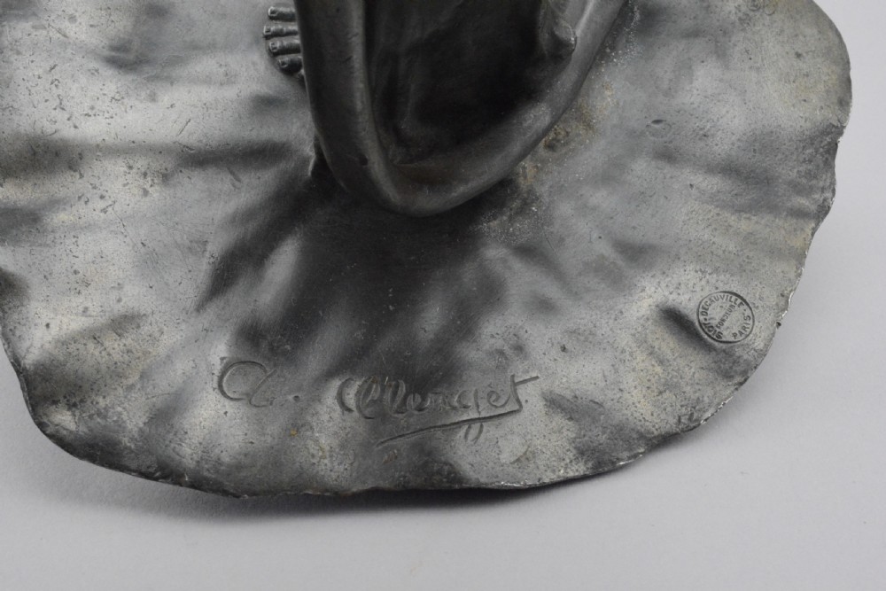 A pair of Art Nouveau pewter candlesticks modelled as draped female figures embracing large flower blossoms on lily pad bases. View IV
