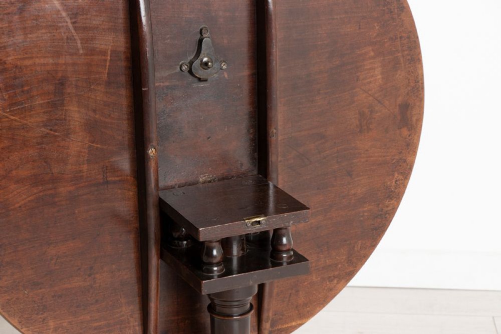 An eighteenth-century circular mahogany tilt-top table featuring a birdcage mechanism, turned central stem, and tripod cabriole legs. View X