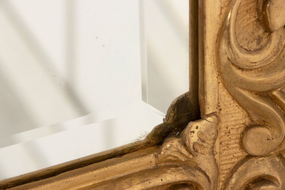 A 19th-century Italian giltwood wall mirror featuring an ornate carved floral cresting and rectangular bevelled glass. View V