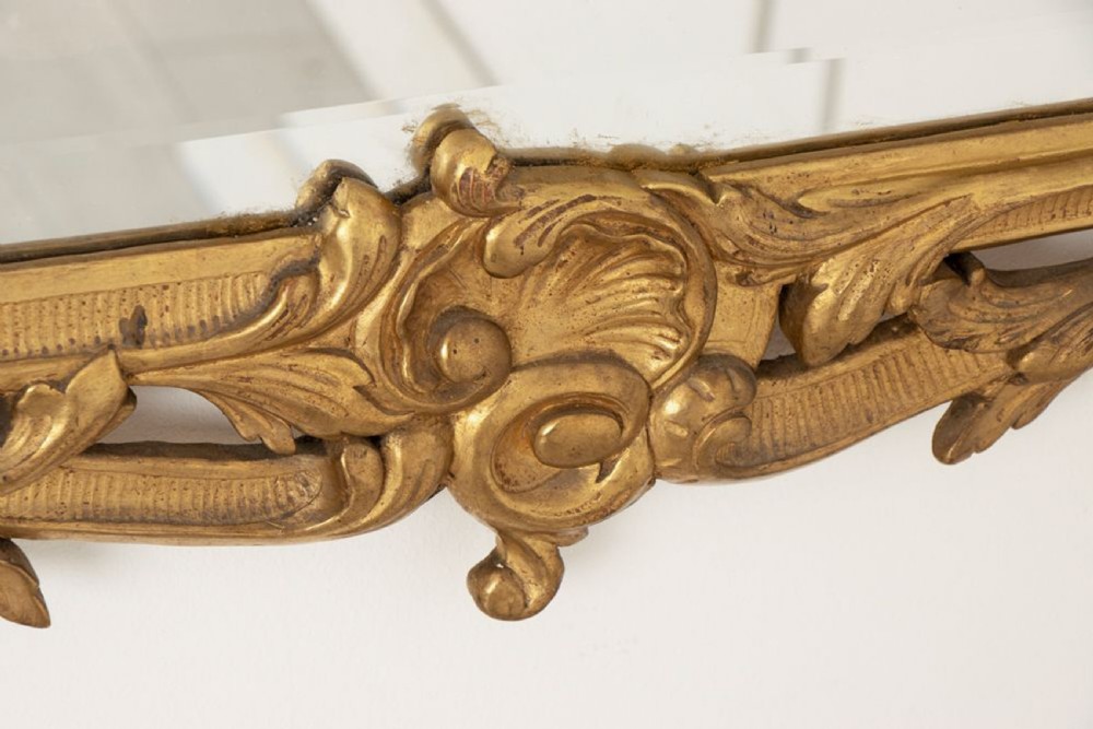 A 19th-century Italian giltwood wall mirror featuring an ornate carved floral cresting and rectangular bevelled glass. View VI