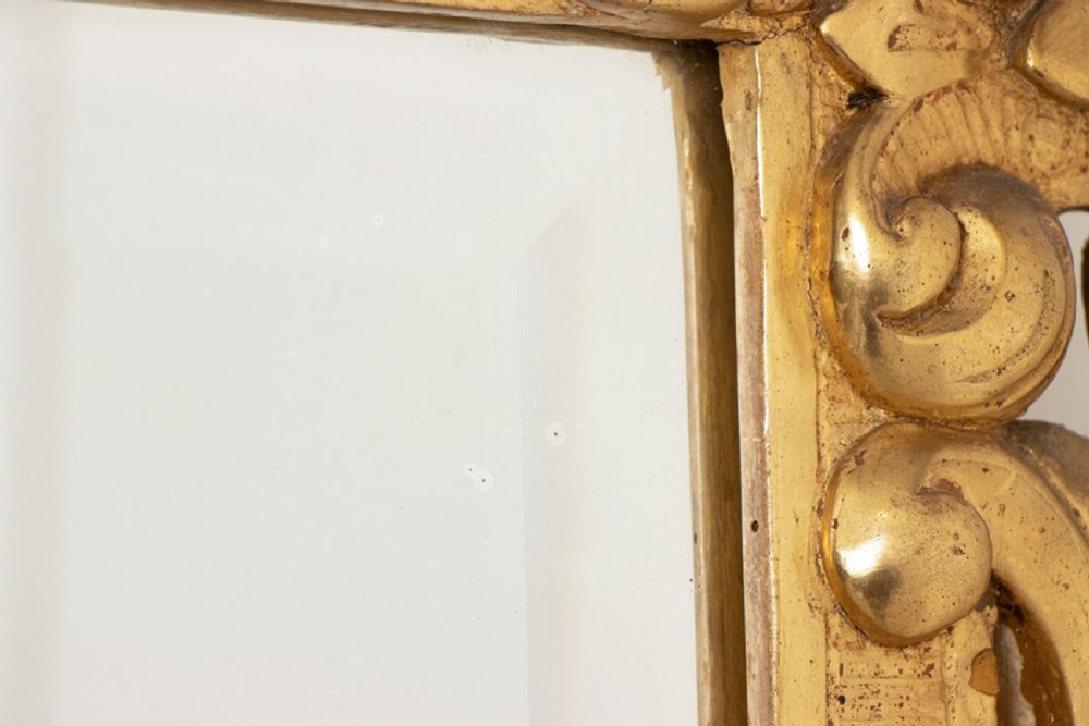 A 19th-century Italian giltwood wall mirror featuring an ornate carved floral cresting and rectangular bevelled glass. View VII