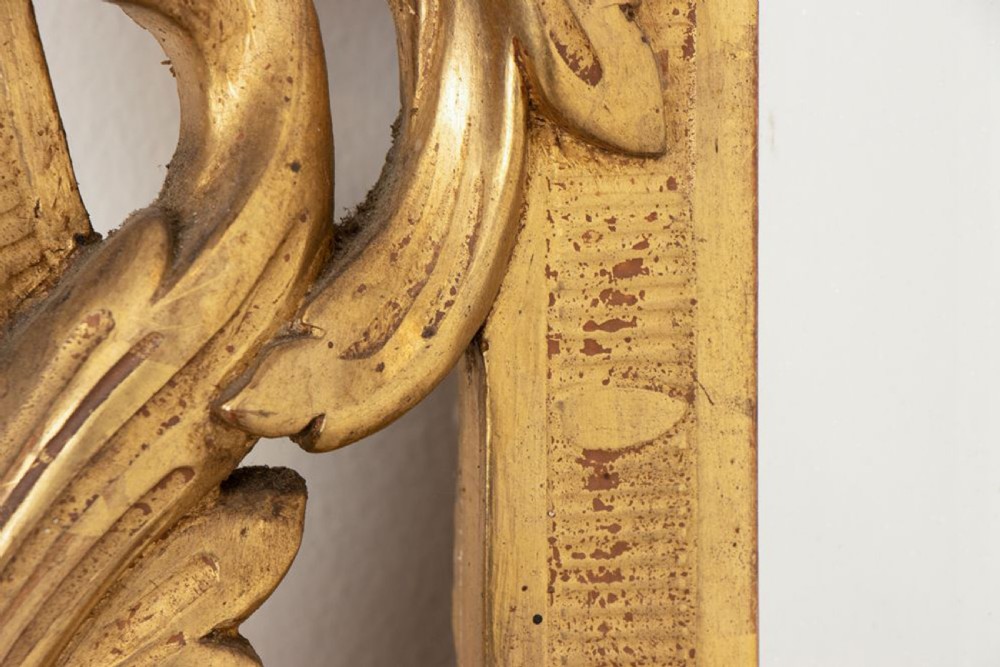 A 19th-century Italian giltwood wall mirror featuring an ornate carved floral cresting and rectangular bevelled glass. View VIII