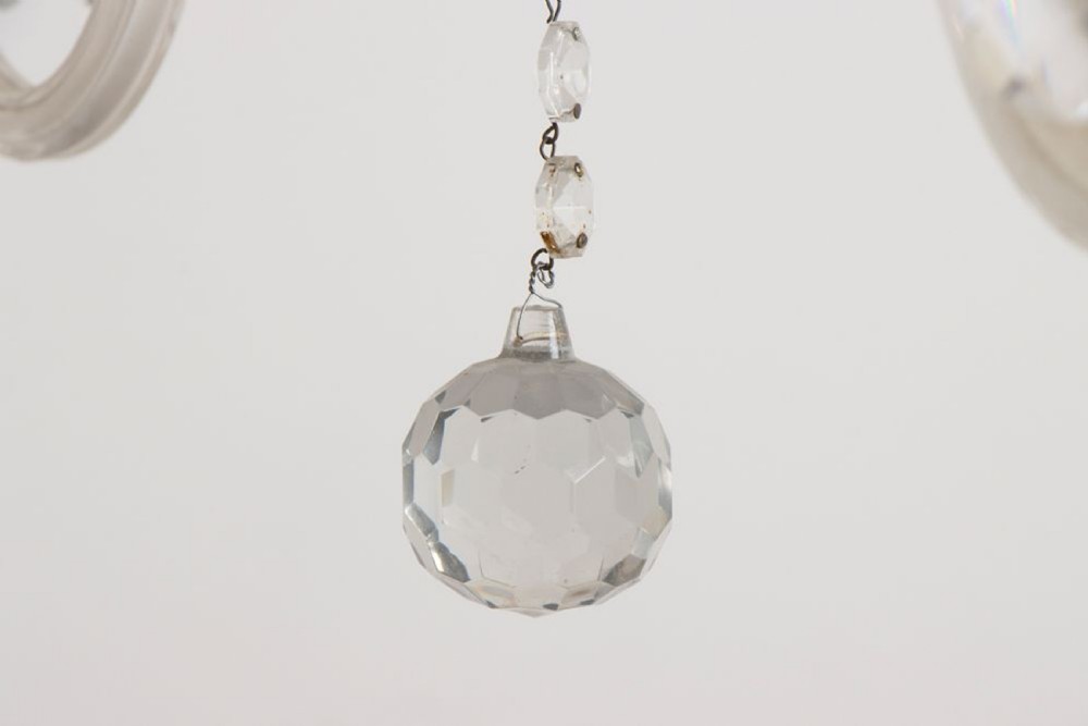 A 1920s clear glass chandelier featuring curved swan-style arms, candle-shaped light sockets, hanging crystal droplets, and a silver ceiling chain. View VIII
