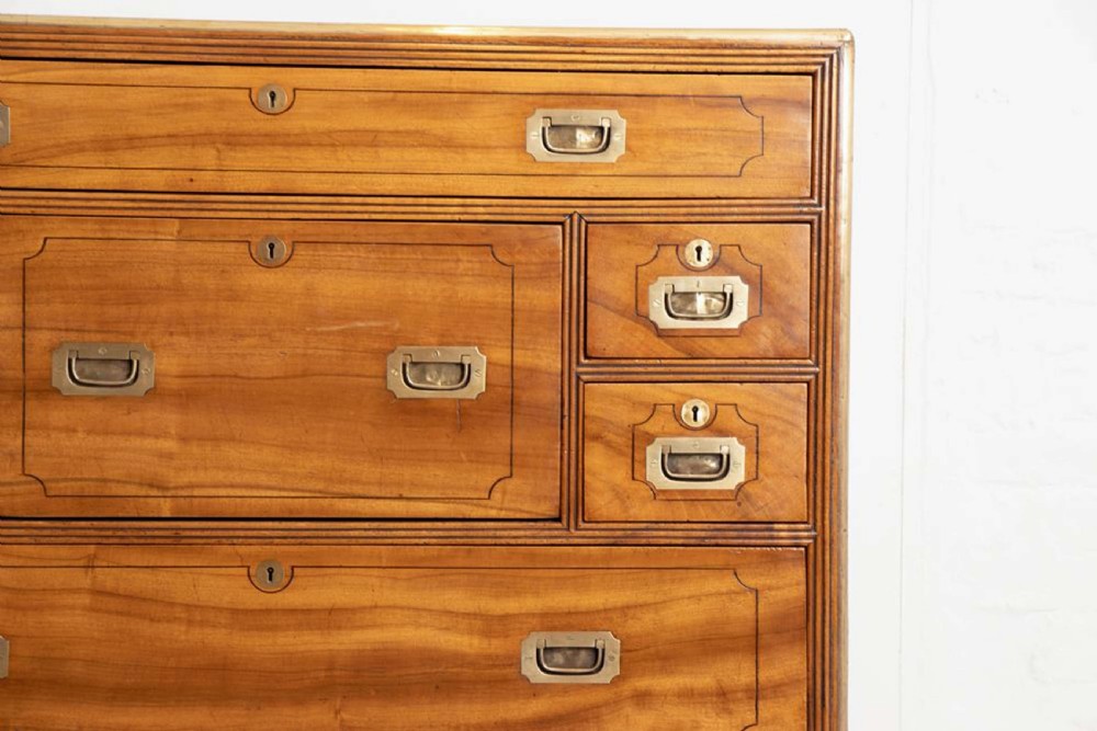An antique 19th-century camphorwood military campaign secretaire chest featuring flush brass handles, geometric drawer borders, and turned feet. View VIII