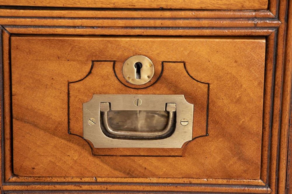 An antique 19th-century camphorwood military campaign secretaire chest featuring flush brass handles, geometric drawer borders, and turned feet. View X