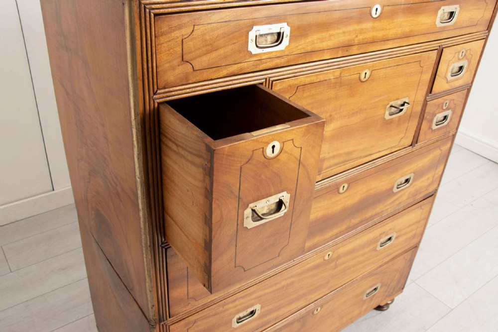 An antique 19th-century camphorwood military campaign secretaire chest featuring flush brass handles, geometric drawer borders, and turned feet. View XV
