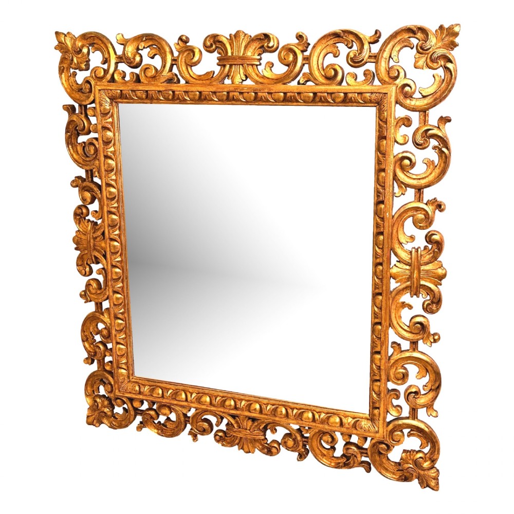 A late 18th-century Italian rectangular wall mirror featuring an intricate carved openwork giltwood frame with scroll motifs and acanthus leaf details.