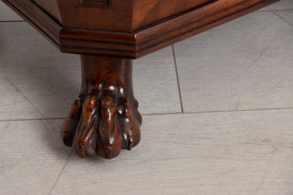 A Georgian mahogany sarcophagus-shaped cellarette featuring a stepped lid, brass escutcheon, flame veneer panels, and carved paw feet. View VII