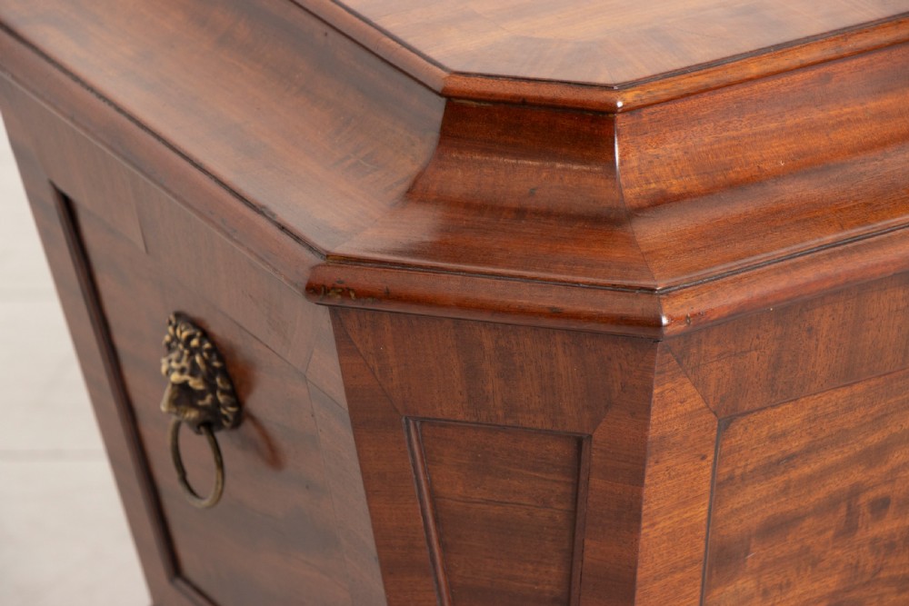 A Georgian mahogany sarcophagus-shaped cellarette featuring a stepped lid, brass escutcheon, flame veneer panels, and carved paw feet. View VIII