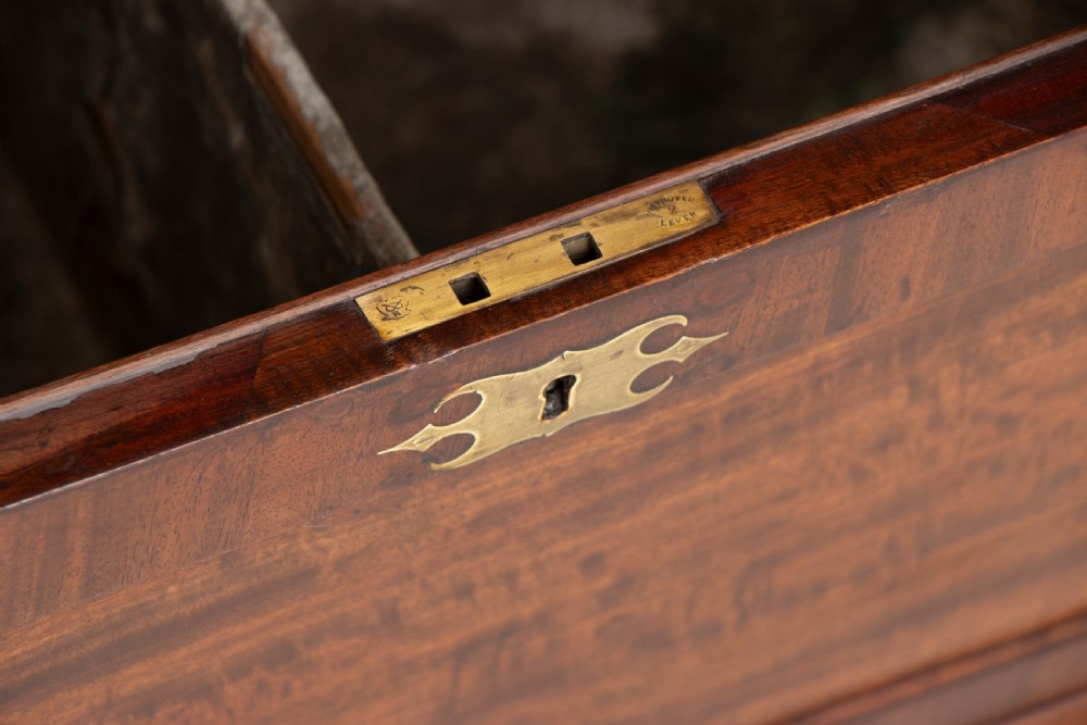 A Georgian mahogany sarcophagus-shaped cellarette featuring a stepped lid, brass escutcheon, flame veneer panels, and carved paw feet. View X