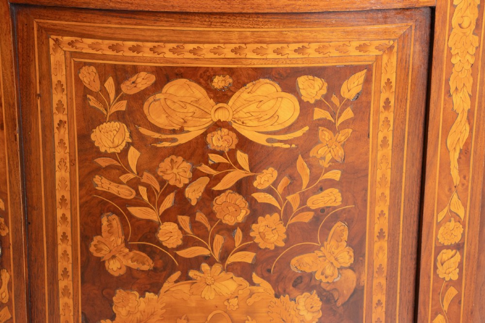 An antique two-tier Dutch corner cupboard featuring detailed floral marquetry inlay, an arched glazed upper door, and a solid lower cupboard door. View IX
