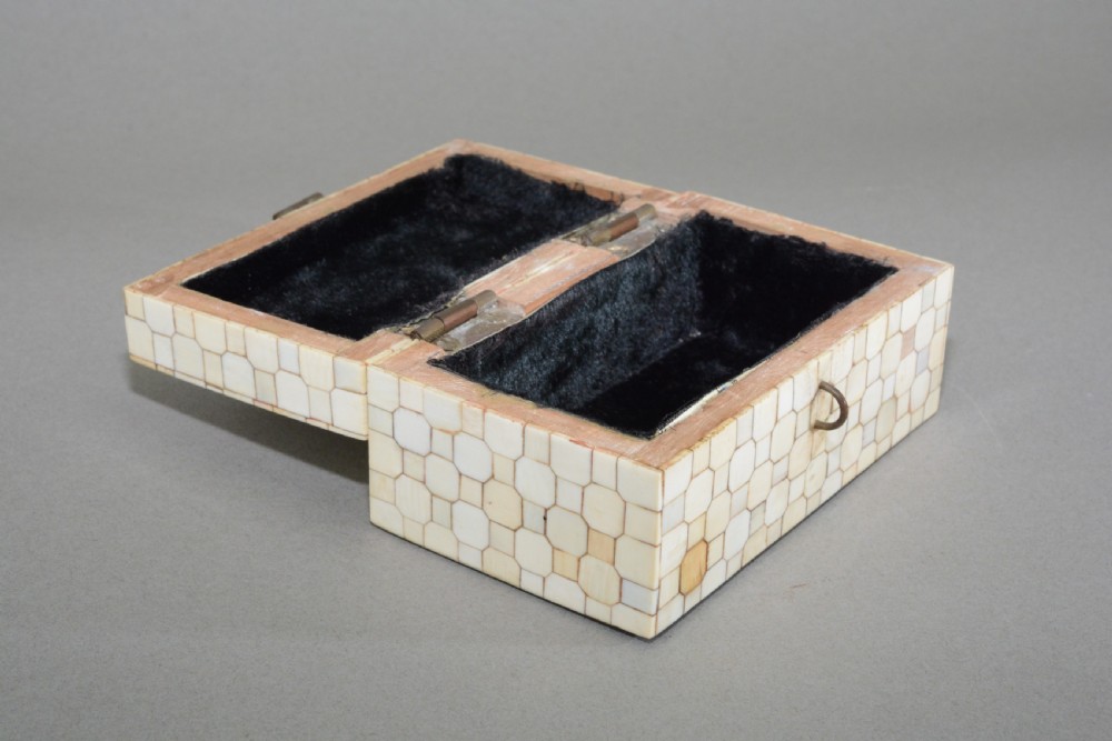A small rectangular box coated in a mosaic pattern of off-white specimen bone tiles with a central brass latch. View II