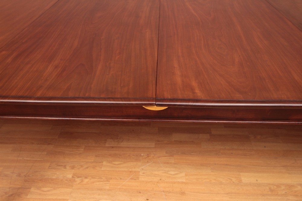 A extended Cuban mahogany dining table featuring additional insert leaves, a polished rectangular top, and four reeded turned legs on brass castors. View III