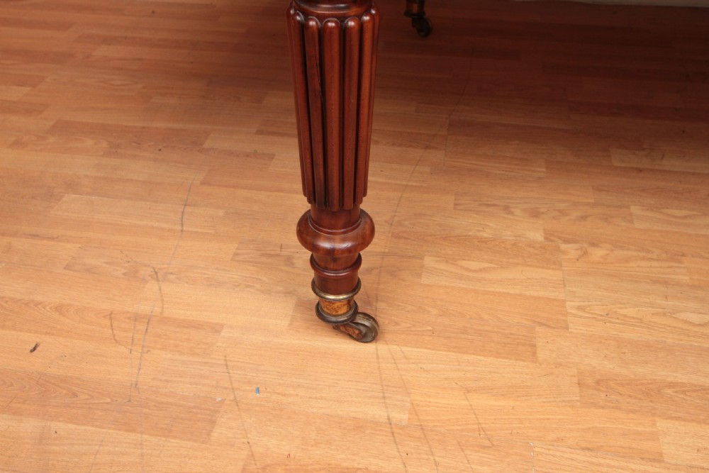 A extended Cuban mahogany dining table featuring additional insert leaves, a polished rectangular top, and four reeded turned legs on brass castors. View VI